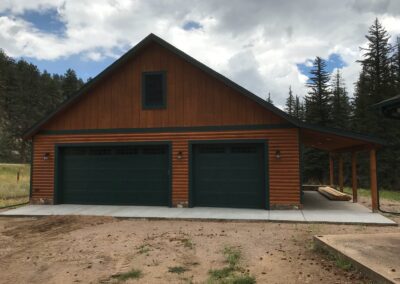 A garage with a green roof and two garage doors.