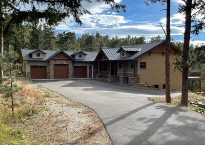 A home with two garages and a driveway in the woods.